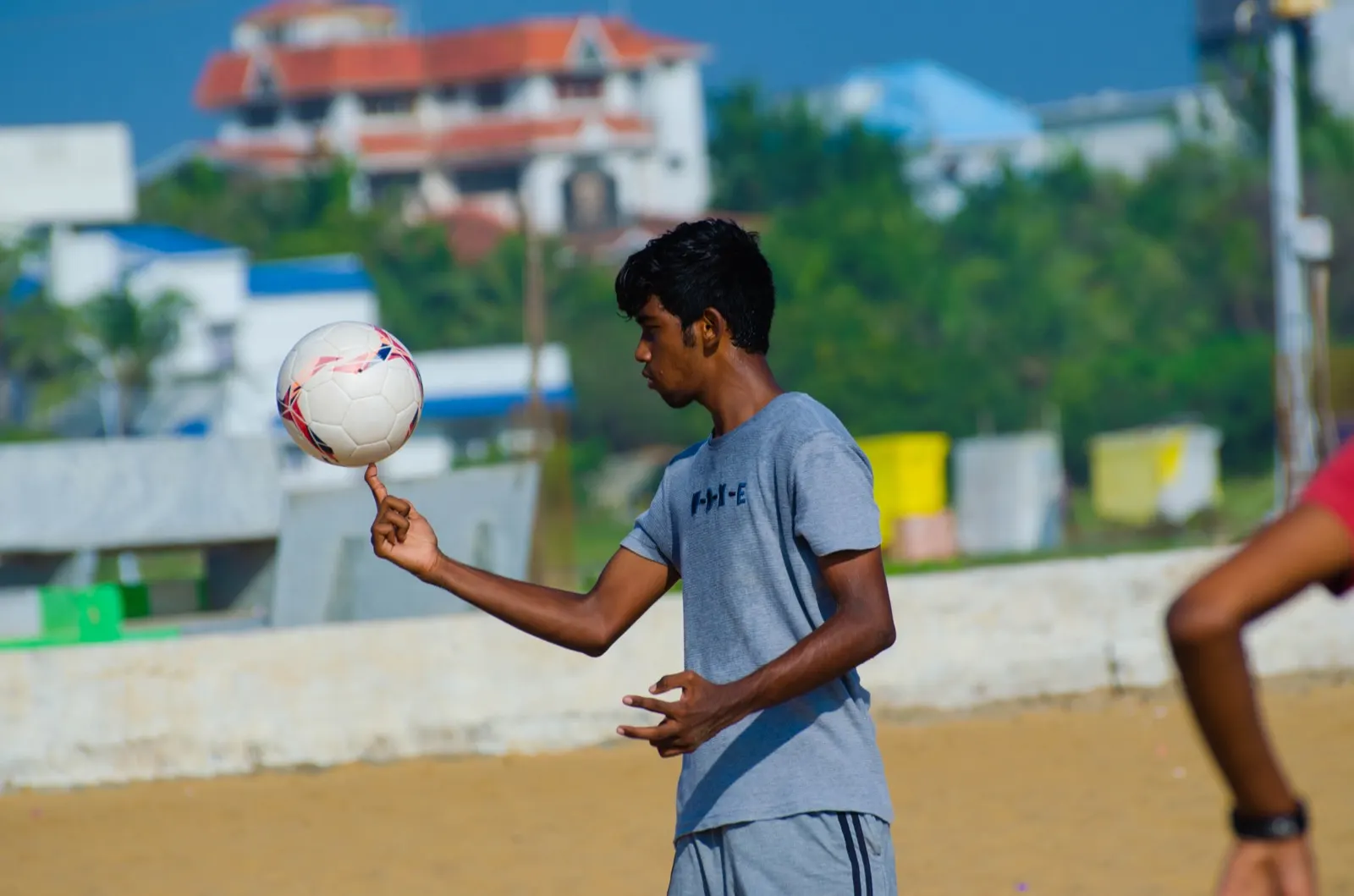 Boy balancing a football on one finger at the beach